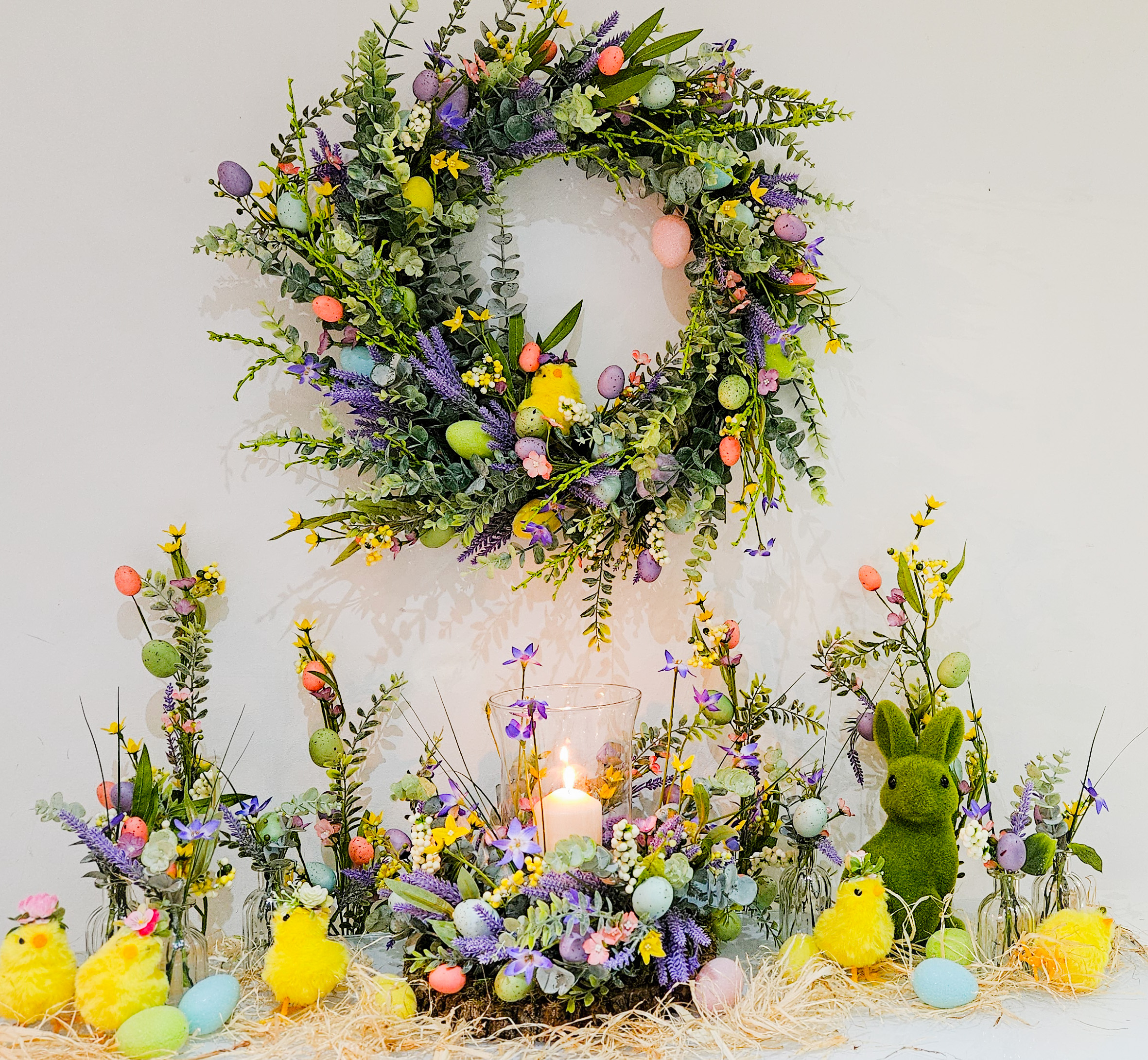 Easter decorative display featuring a pillar candle, seasonal wreath and colourful Spring themed floral decor.